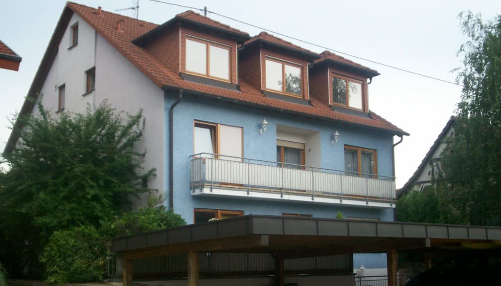 Wohnhaus von der Straße, blaue Fassade, Dachgeschoss und Carport