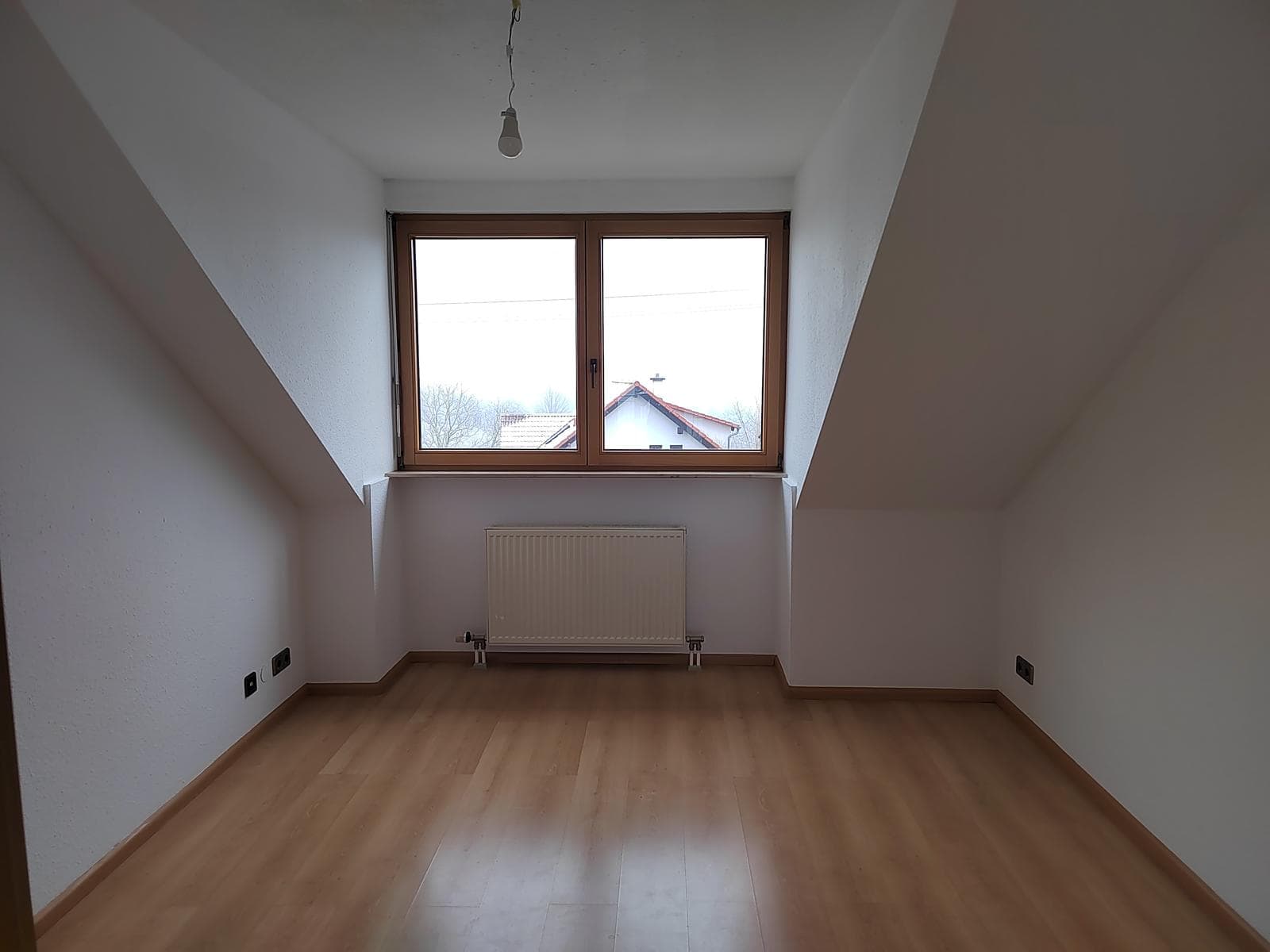Kleineres Zimmer mit Parkett, einem Fenster und Dachschrägen links und rechts