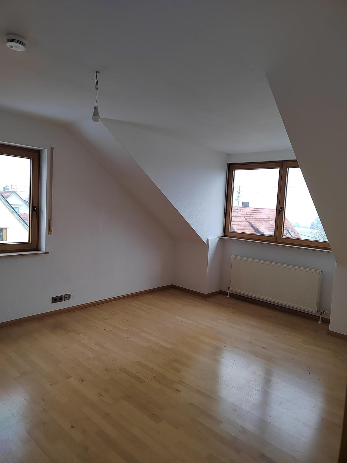 Schlafzimmer mit Parkett, Dachschräge und zwei Fenstern